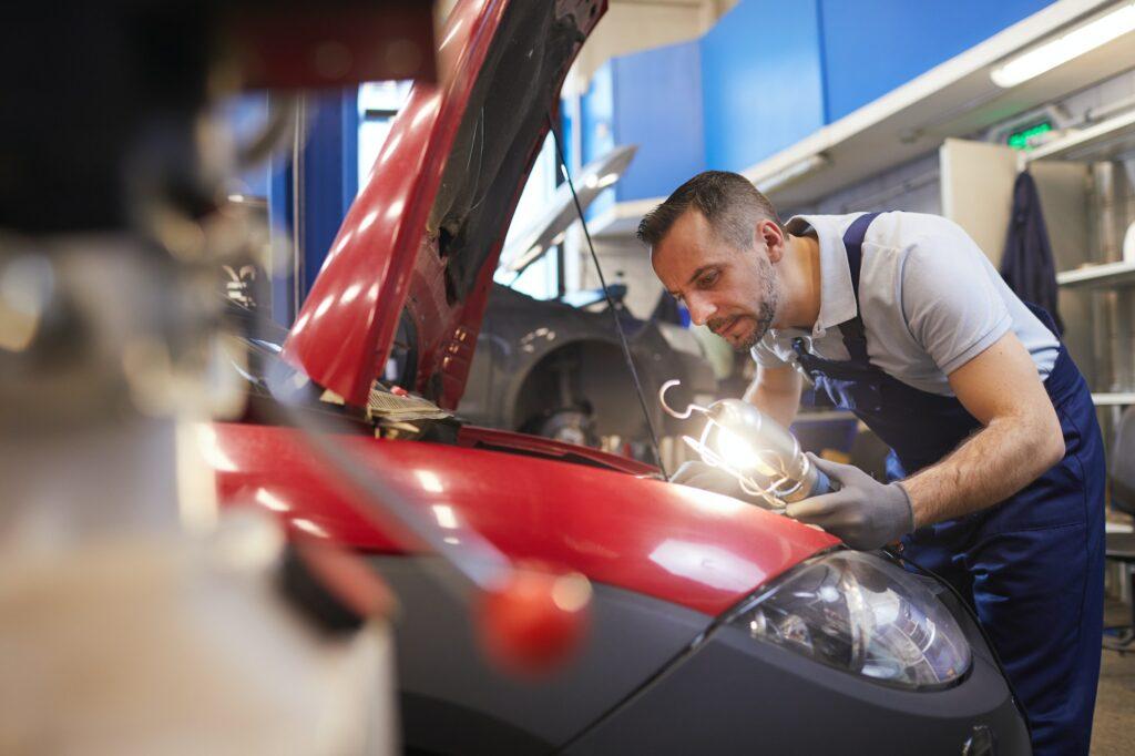Mechanic Inspecting Car in Garage Workshop