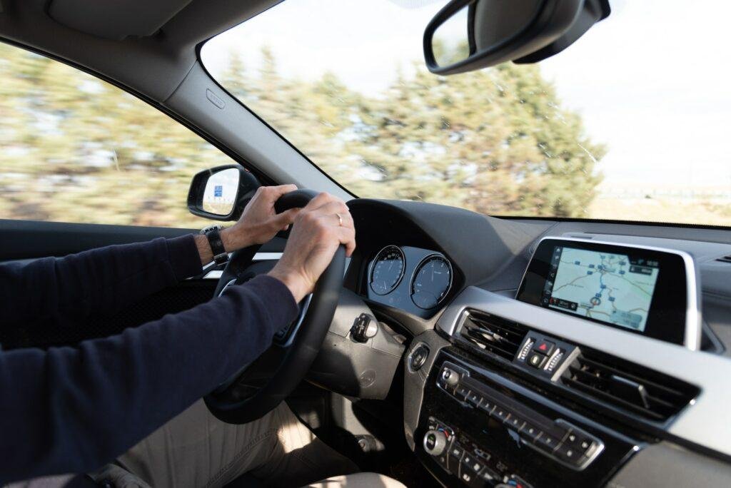 Side view of man driving BMW X2 car with navigation GPS